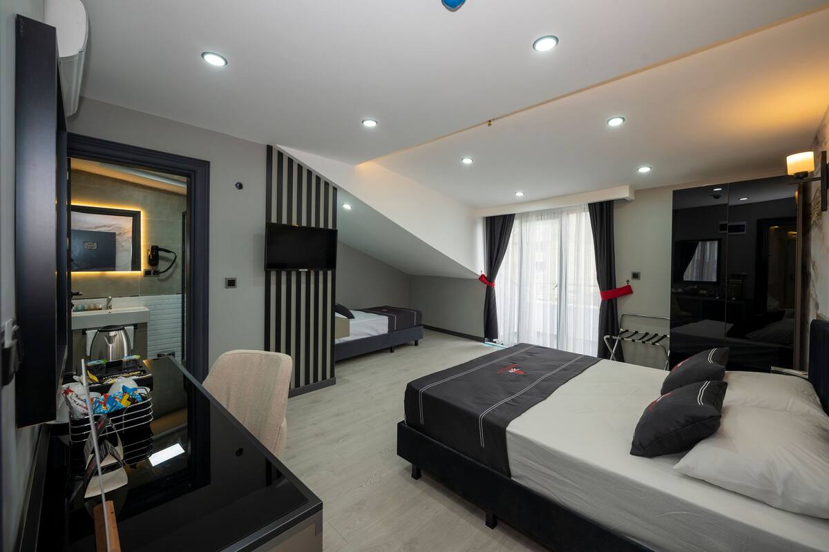 A modern hotel room with a large bed, a desk, a mirror, and a TV.