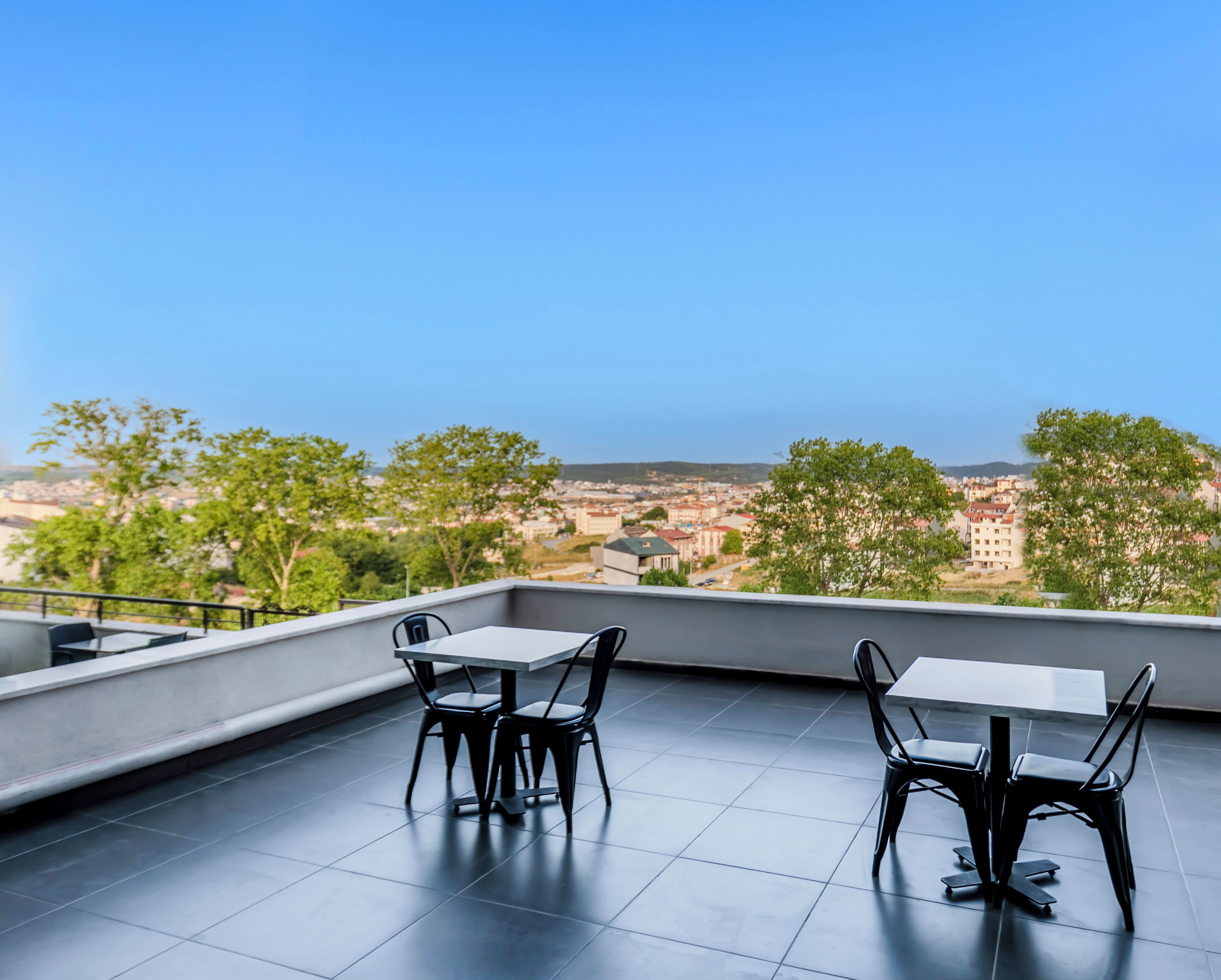 Una terraza con dos mesas y sillas, que ofrece vistas a un paisaje urbano.
