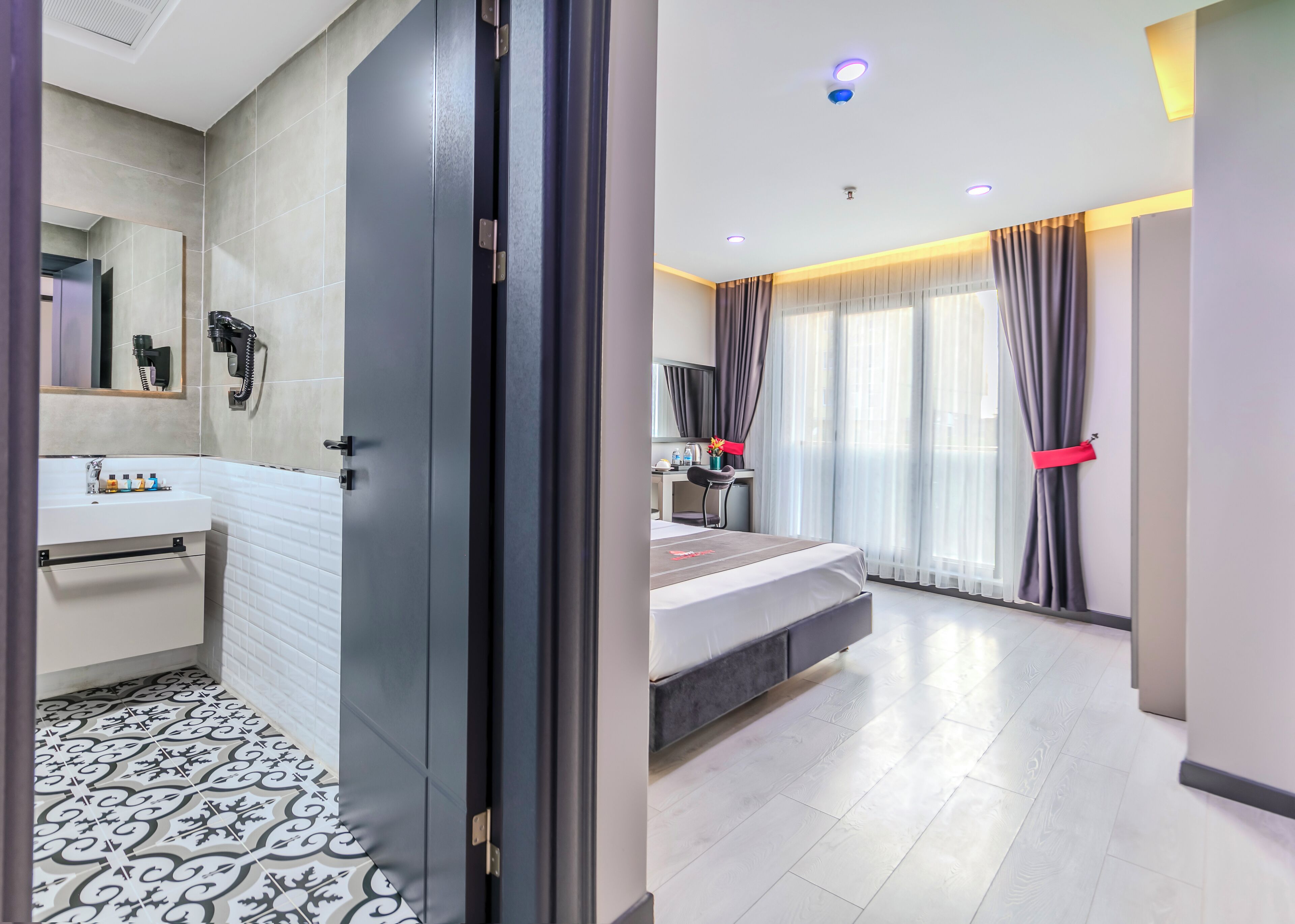 Une chambre d’hôtel moderne, dotée d’un grand lit, d’un bureau et d’une salle de bain avec un lavabo et un miroir.