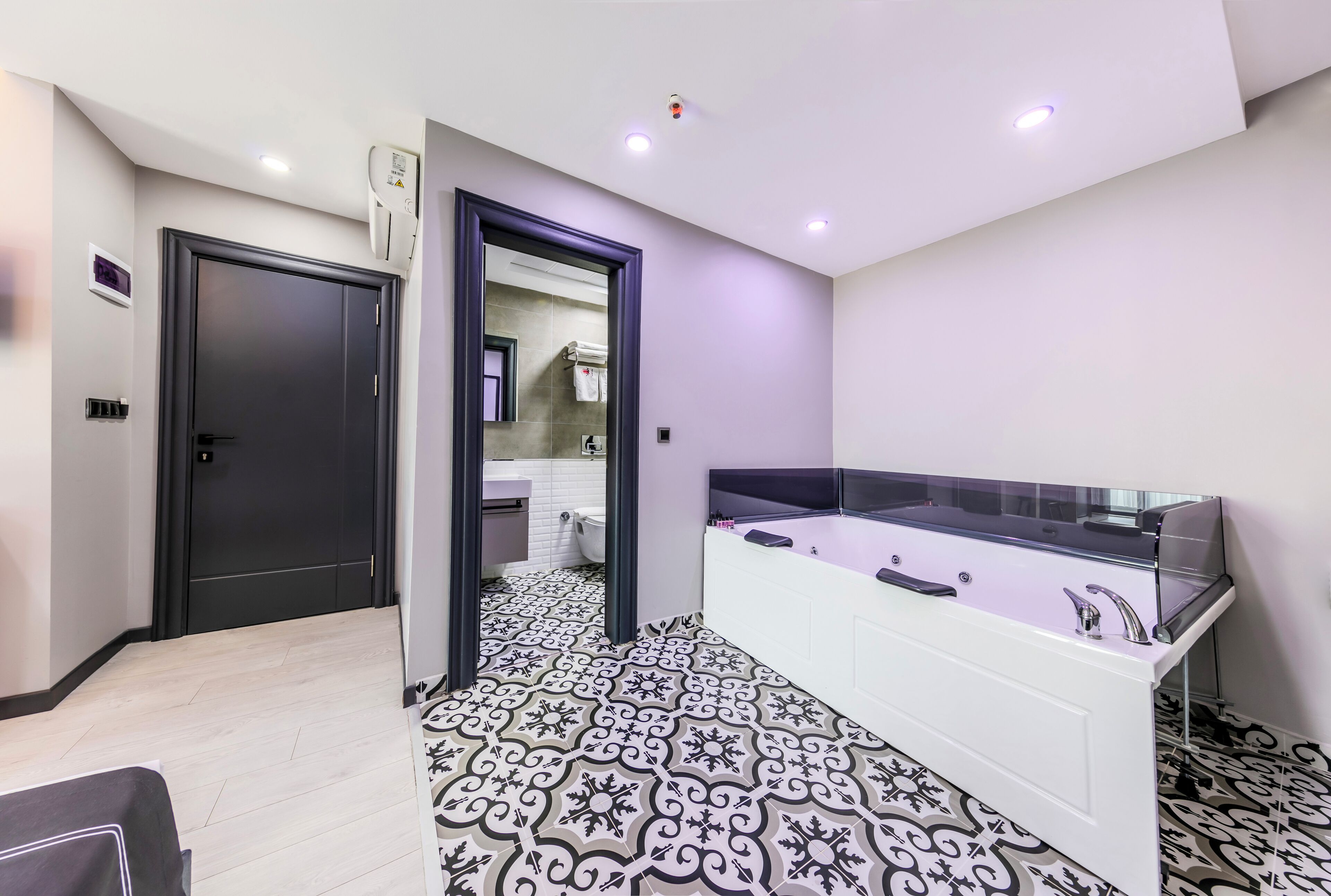 Un baño moderno con una bañera grande, un tocador blanco y baldosas de suelo estampadas.