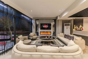 Una sala de estar moderna con chimenea, una pantalla de televisión grande y asientos cómodos.