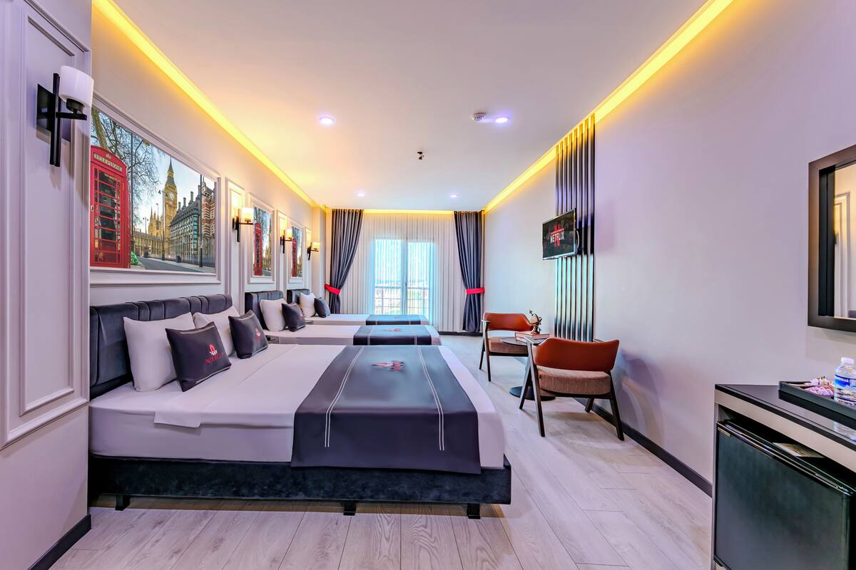 A hotel room with two beds, a desk, a chair, and a TV.