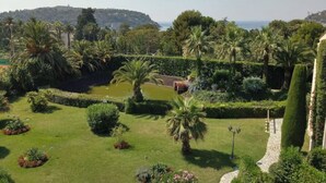 Un jardin bien entretenu, avec différentes espèces de plantes et un étang, entouré de collines et surplombant un ciel dégagé.
