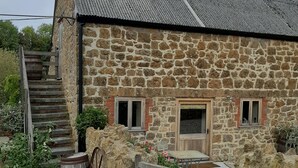 A stone building with a metal roof, a wooden staircase, and a gate labeled "Cider Barn". - Romantic getaway (Donyatt)