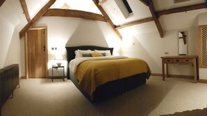 A bedroom with a bed, a bedside table, a lamp, a radiator, and a wooden desk. - Romantic getaway (Donyatt)