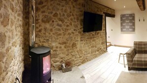 A rustic interior with a stone wall, a fireplace, a plaid sofa, and a wooden door. - Romantic getaway (Donyatt)