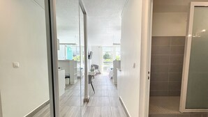 Ein modernes Interieur mit einem Flur, der zu einem Balkon führt, mit Fliesenboden und Glastür.