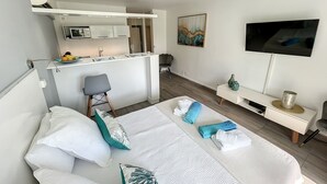 Ein modernes Hotelzimmer mit Bett, Schreibtisch, Sessel, Fernseher und einem Bild an der Wand.