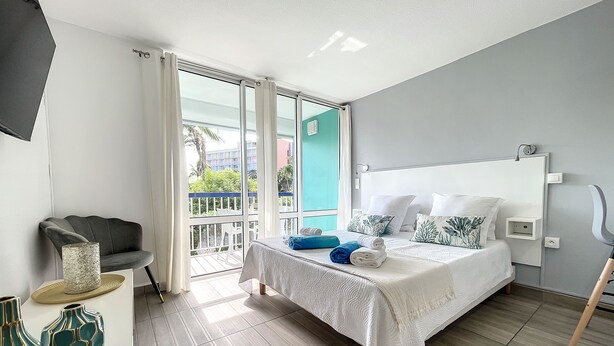 Ein modernes Hotelzimmer mit einem großen Bett, einem Balkon mit Aussicht und einer Sitzecke mit einem Sessel und dekorativen Vasen.