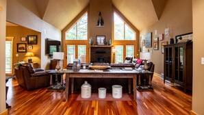 Un salón amplio con techo alto, chimenea y ventanas grandes.