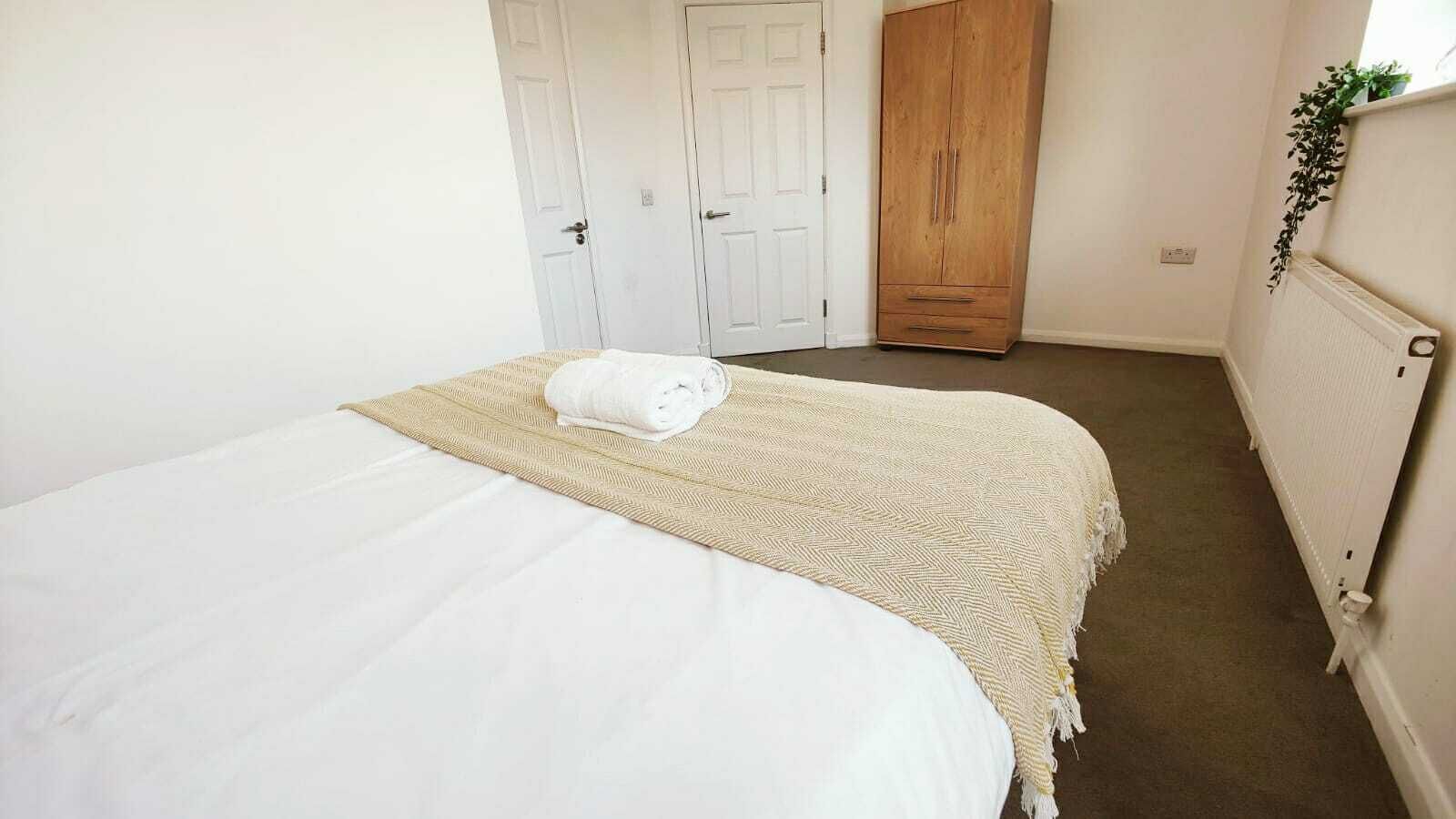 A bedroom with a bed, a wooden wardrobe, and a radiator.