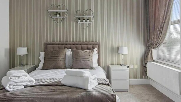 A hotel room with a bed, two nightstands, a radiator, and heart-shaped wall decorations.