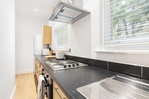 A modern kitchen with a black countertop, stainless steel sink, and a built-in range hood.