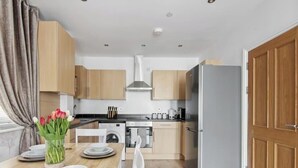 Una cocina funcional con armarios de madera, estufa de acero inoxidable, lavadora y refrigerador.
