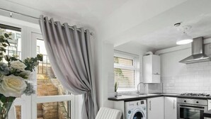 Une cuisine moderne avec des meubles blancs, un four encastré et un lave-linge.