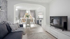 Un salon moderne comprenant un canapé, un téléviseur et un coin repas avec une table et des chaises.