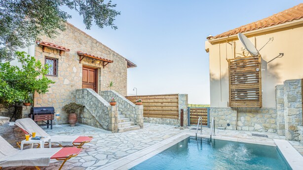 A stone building with a pool, outdoor furniture, and a wooden fence. - Olive Villas (Platanias)
