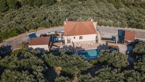 An aerial view of a house with a swimming pool, surrounded by trees and a hilly landscape. - Olive Villas (Platanias)
