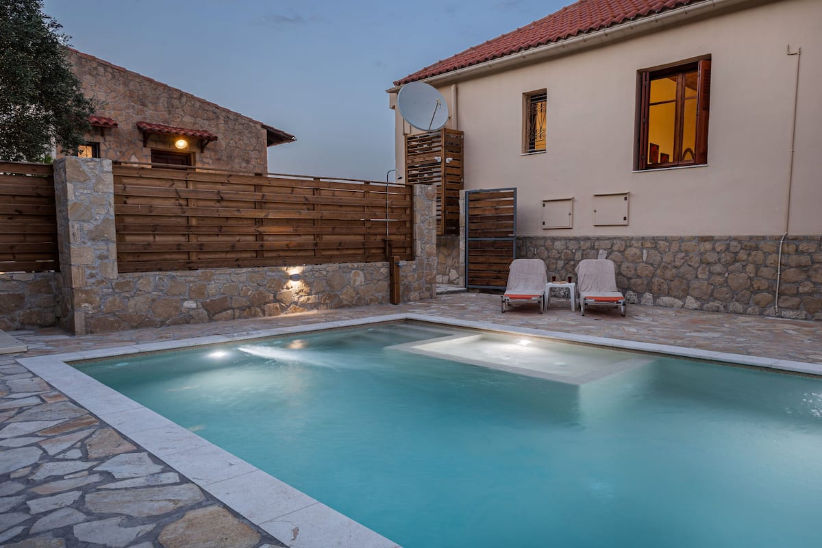 Ein Pool mit zwei Liegestühlen und einer Steinmauer.