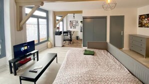 Een moderne slaapkamer met een bed, een televisie, een bureau en een kledingkast.