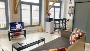 Een moderne woonkamer met een bank, een salontafel, een televisie en een eethoek met een tafel en stoelen.