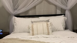 A bed with a white canopy, white pillows, and a fluffy beige blanket. - Be our guest BOHO 2.0 (Charlotte)