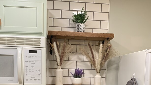 A kitchen with a microwave, oven, and refrigerator. There are shelves with decorative plants and kitchen utensils. - Be our guest BOHO 2.0 (Charlotte)