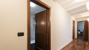 A hallway with wooden flooring, a wooden door, and a light switch on the wall. - Toscanella 3 Bedrooms by Mmega (Florence)