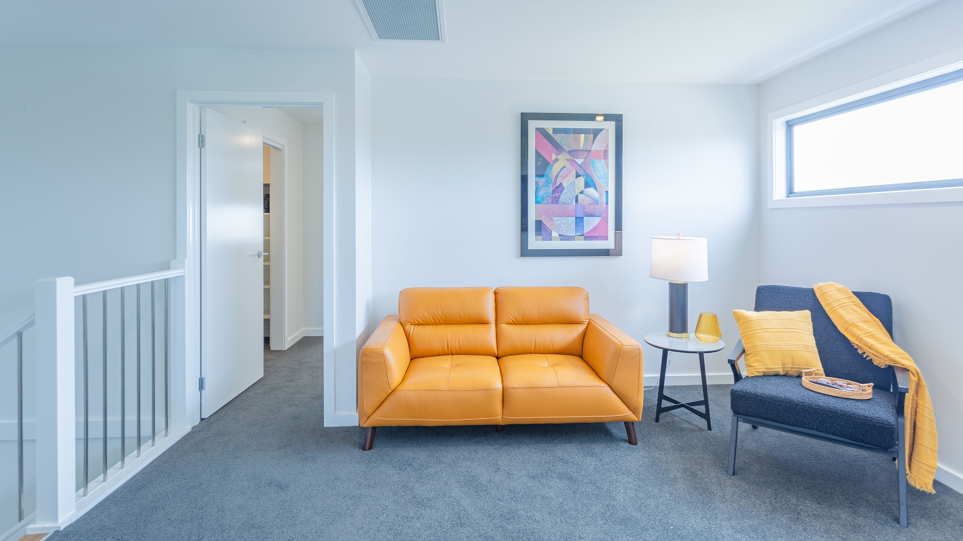 A room with a sofa, a chair, a lamp, and a painting on the wall.