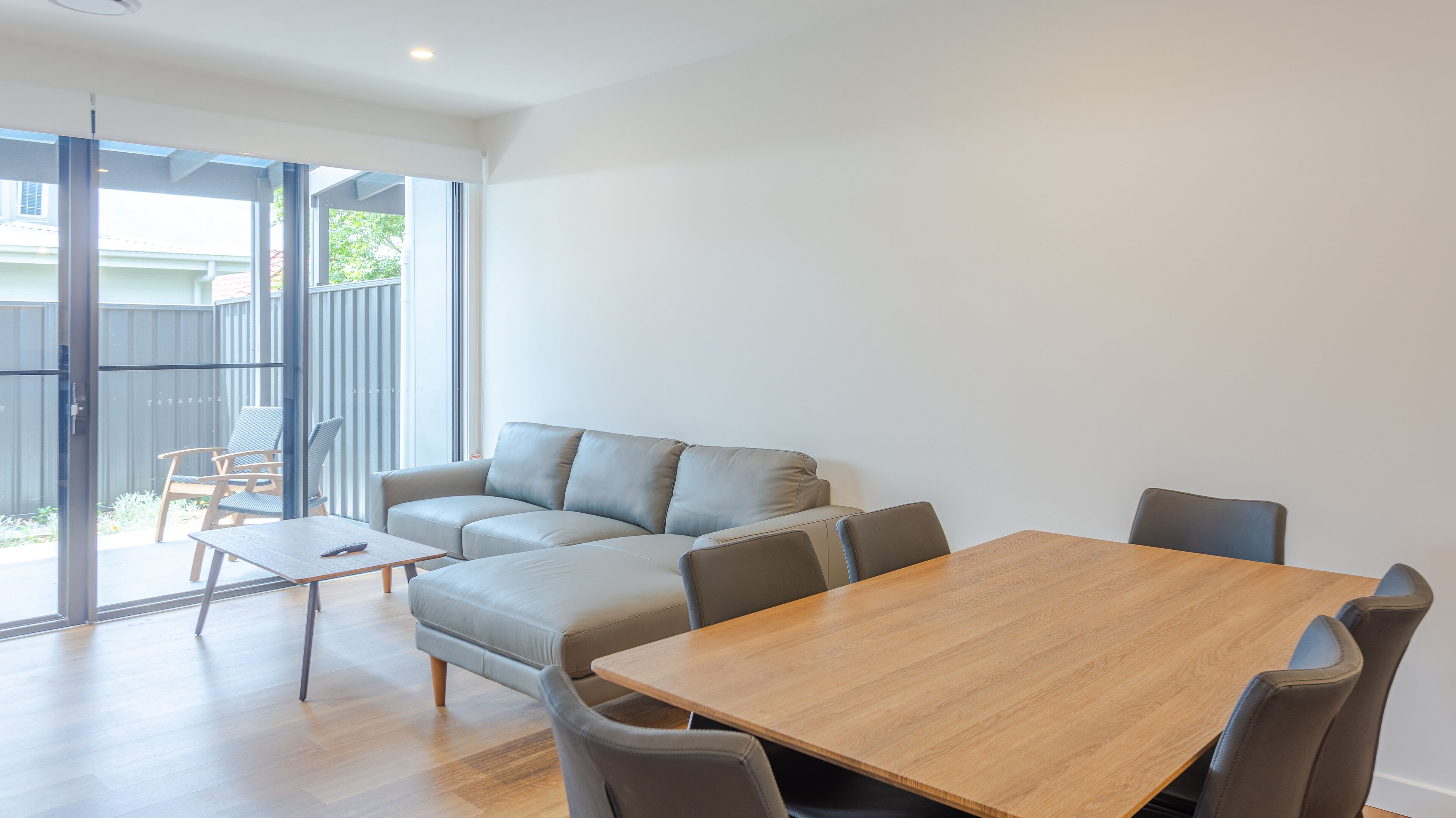 A modern living room with a sofa, a coffee table, and a dining table with chairs.