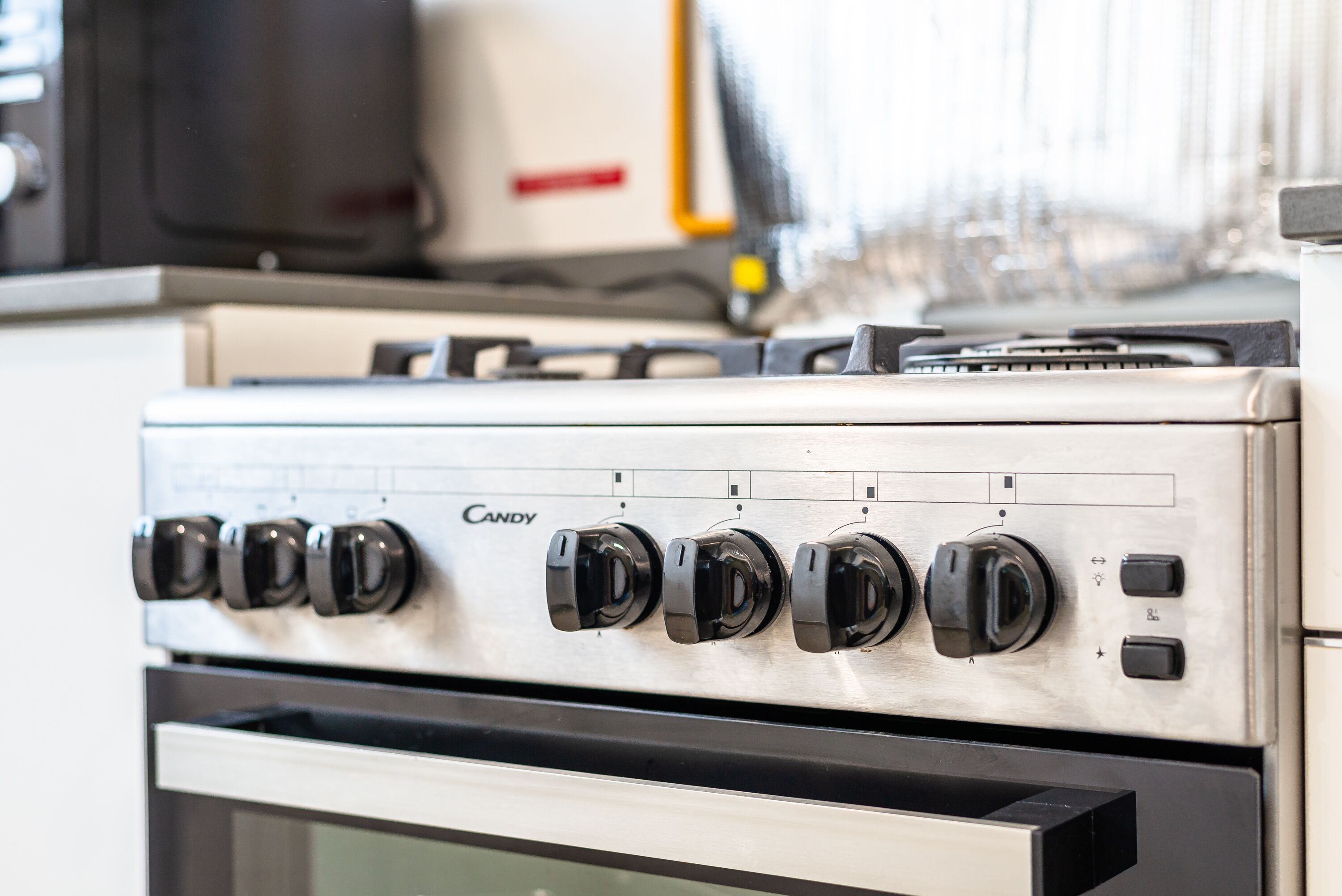 A kitchen with a Candy brand stove, a microwave, and a dishwasher.