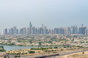 A cityscape with a dense cluster of high-rise buildings, a river, and a highway. - Marco Polo - Park and Skyline Views From this Cozy Apt in JVC (Dubai)
