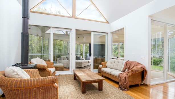 A spacious living area with wicker furniture, a large wooden table, and a fireplace. - Malda's Retreat - Pet Friendly Absolute Beachfront (Culburra Beach)