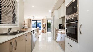 A modern kitchen with stainless steel appliances, a large window with blinds, and a view of the outdoors. - Alkira - Pet Friendly - 4 Mins Walk to Beach (Culburra Beach)