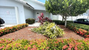 A residential house with a driveway, a garage, and a well-maintained garden with various plants and flowers.