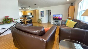 A modern living room with leather sofas, a glass coffee table, and a TV in the background.