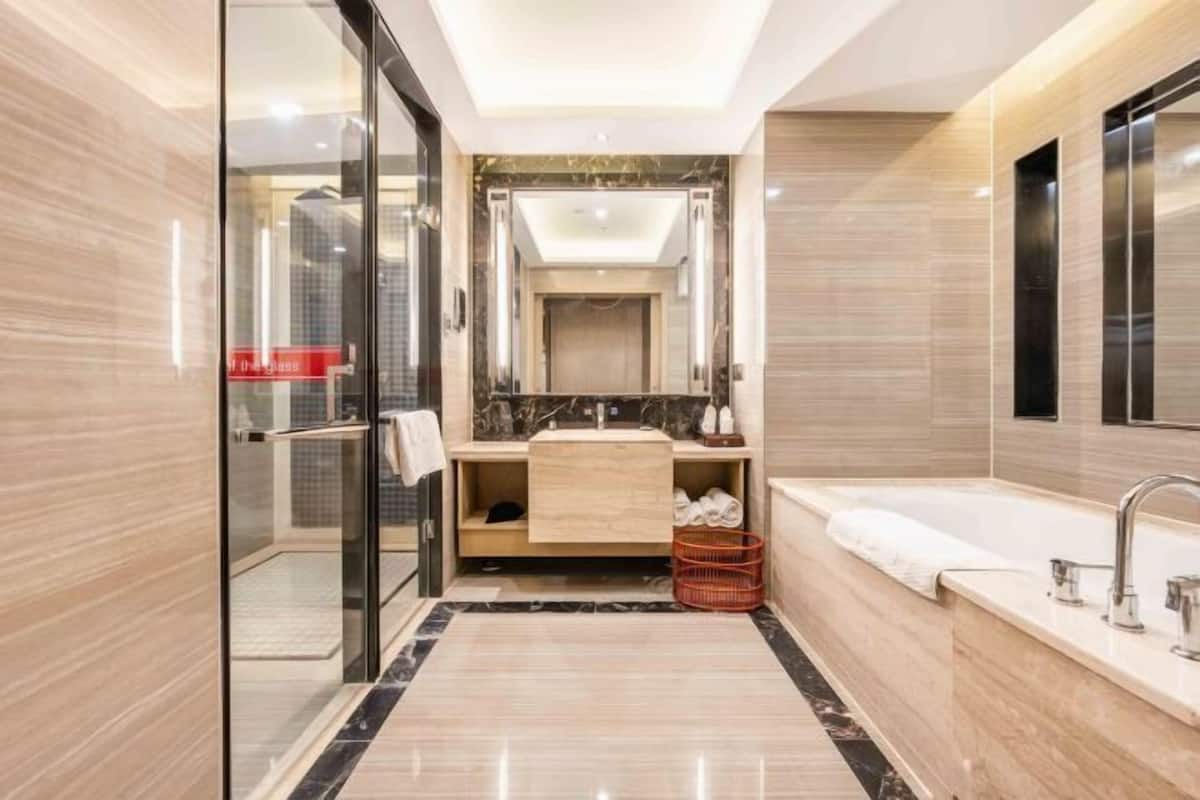 Ein modernes Badezimmer mit Duschkabine aus Glas, großem Spiegel, Badewanne und Waschtisch.