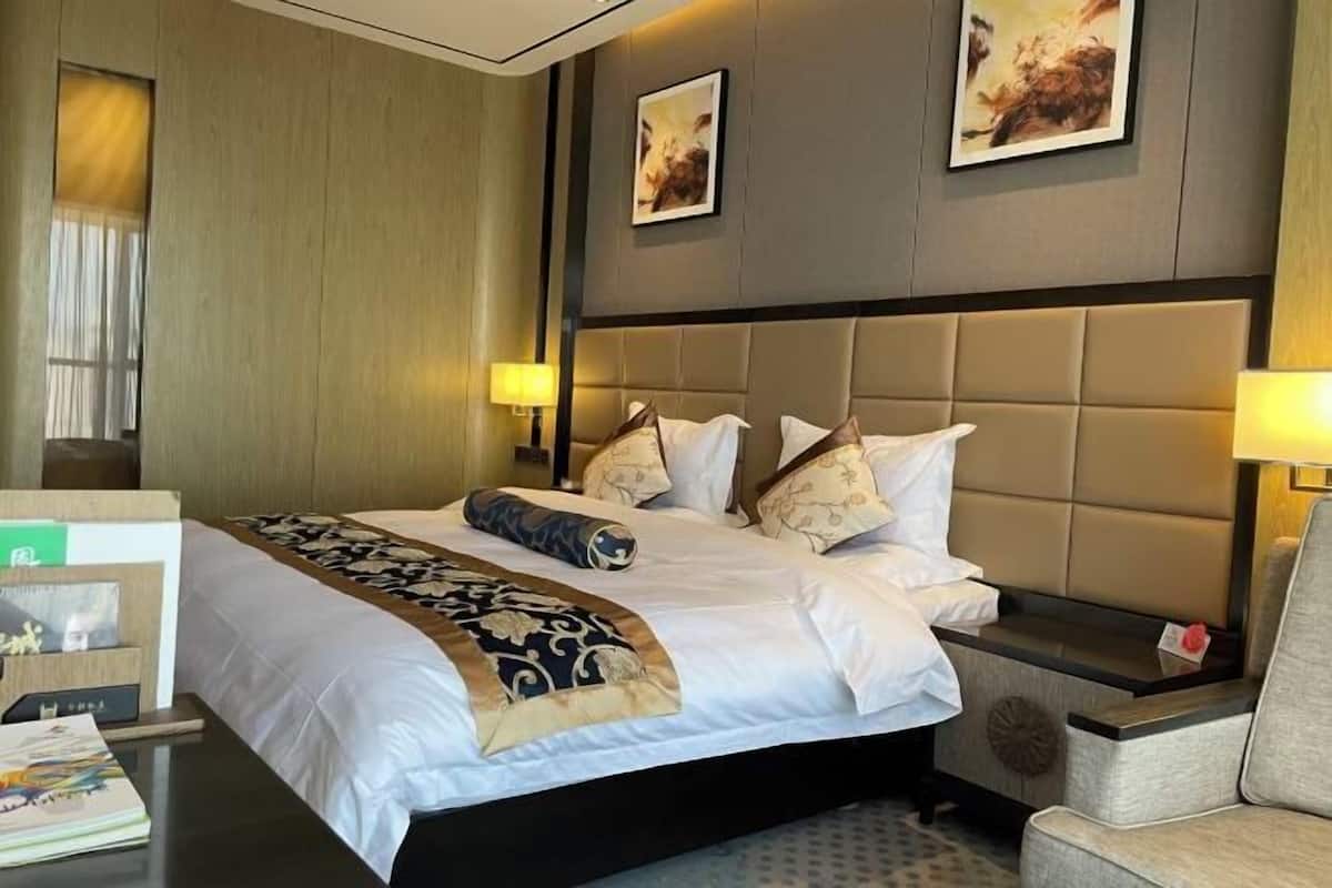 Ein Hotelzimmer mit einem großen Bett, zwei Nachttischen, einem Beistelltisch und einem Sessel.