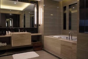 Een moderne badkamer met een grote spiegel, een wastafel met dubbele wastafel en een bad. Op de vloer ligt een witte handdoek.