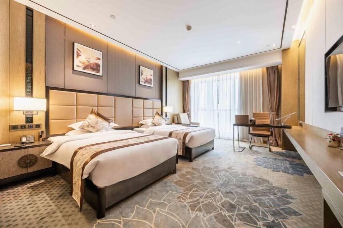 Ein Hotelzimmer mit zwei Betten, einem Schreibtisch und einem großen Fenster.