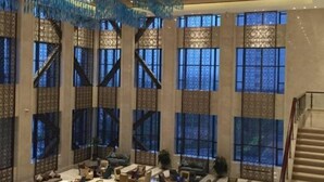 Un vestíbulo amplio con techos altos, ventanas grandes y una escalera.