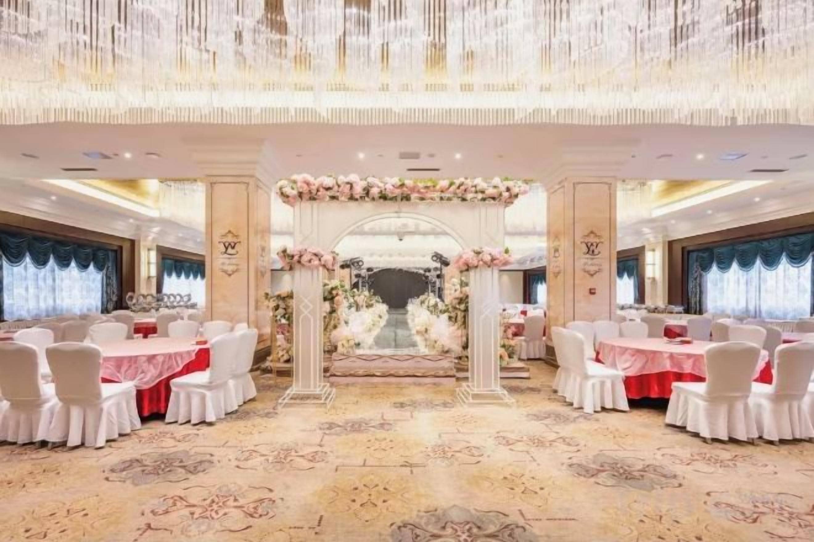 A banquet hall with a central aisle, white chairs, and tables arranged on either side.