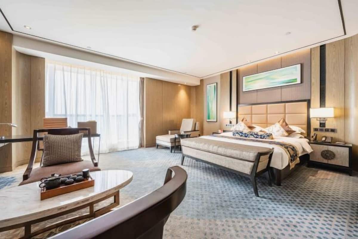 Ein Hotelzimmer mit einem Bett, einem Schreibtisch, einem Sessel, einem Nachttisch und einem großen Fenster.