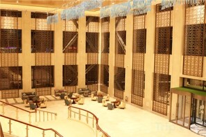 A spacious lobby with multiple seating areas, a staircase, and a reception desk. - Huaqi Earl Hotel (Guyuan)