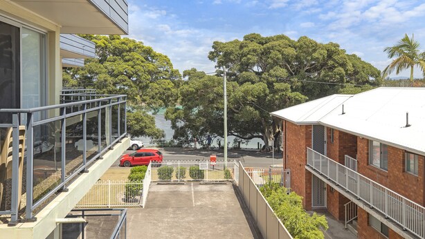 A building with a glass balcony overlooking a parking area and a street. - Lakeside. Breezy. Serendipity. (Forster)