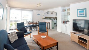 A living room with a sofa, chairs, a coffee table, a TV, and a kitchen area with a dining set. - Lakeside. Breezy. Serendipity. (Forster)
