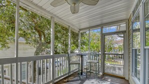 A covered porch with a table and chairs, large windows, and a ceiling fan. - Piper's Retreat - Four Bedroom, Three Bath Dog Friendly Home (Surfside Beach)