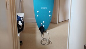 Une planche de surf de couleur turquoise est appuyée contre un mur dans un couloir.