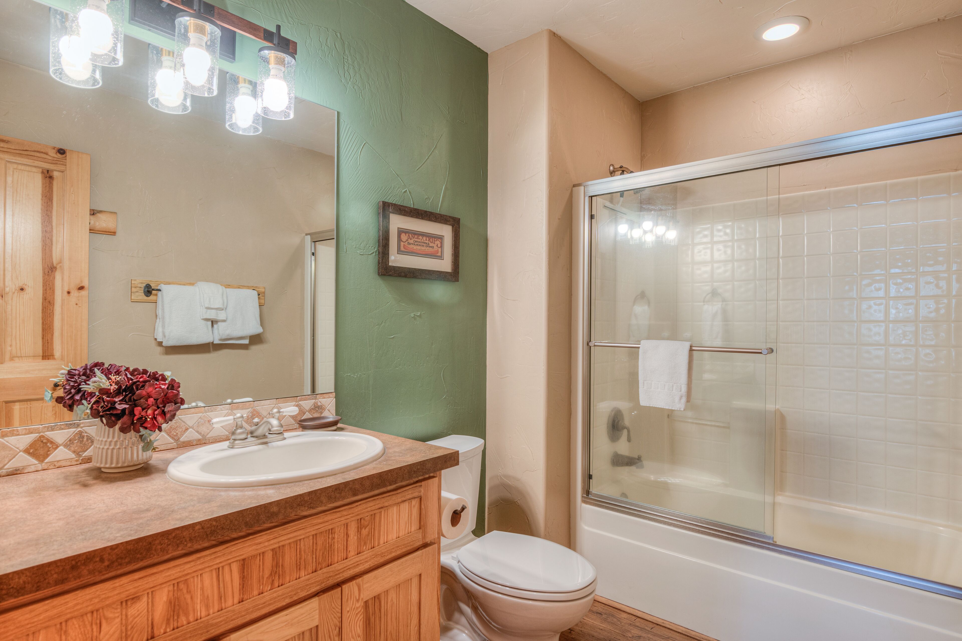 A bathroom with a wooden vanity, a sink, a toilet, and a glass-enclosed shower.
