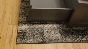 Huoneessa on harmaa metallinen sängynrunko, valkoinen päiväpeite ja harmaa matto.